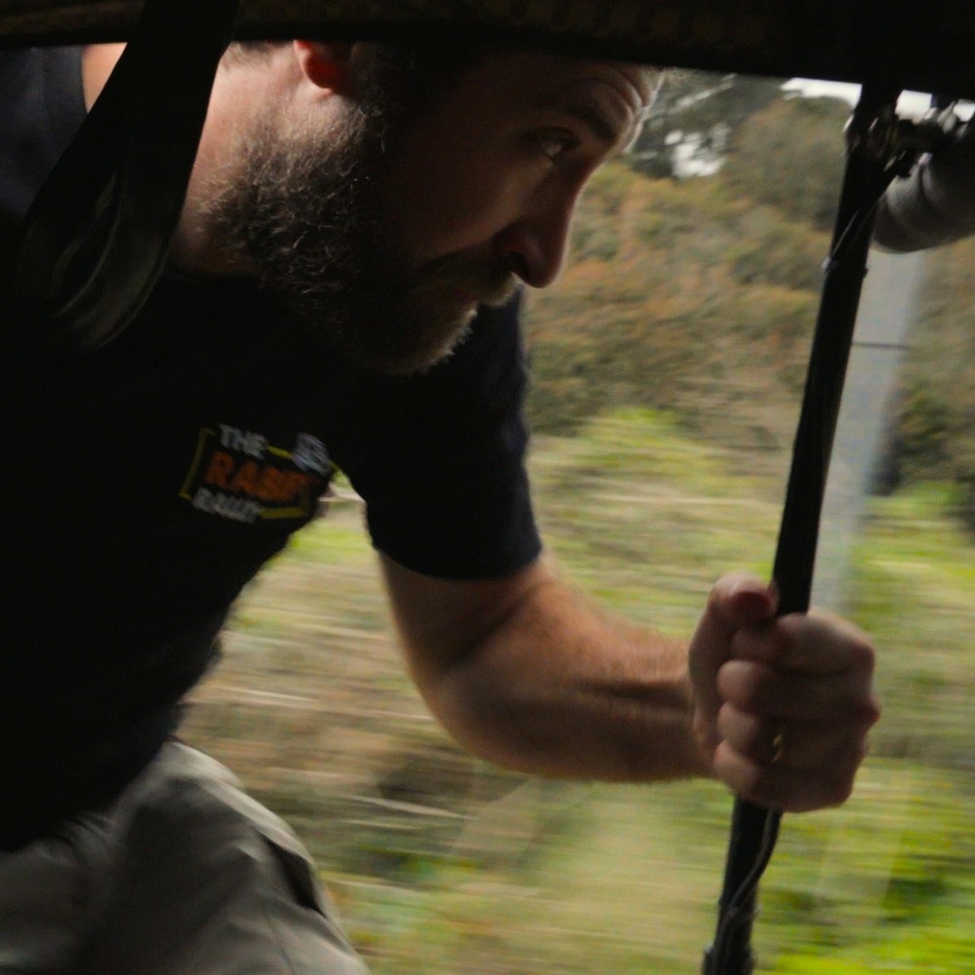 Fred holding on to the side of the tuk tuk